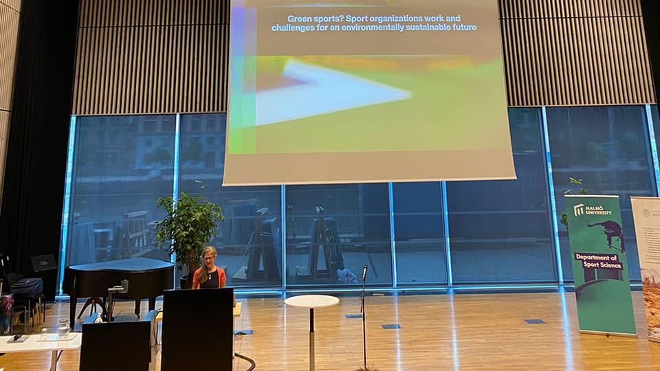 Forskaren Susanna Hedenborg står framför en talarstol i en stor konferenslokal 