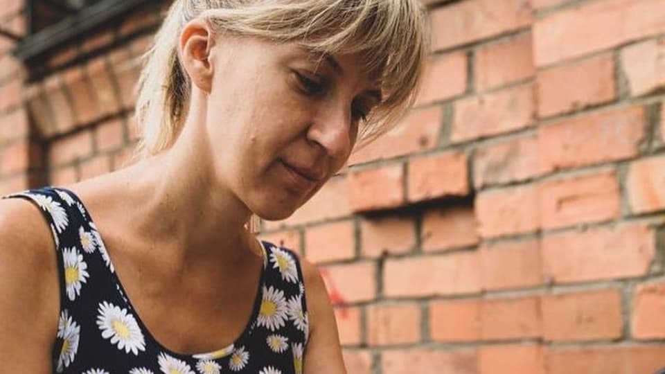 Olga Milinchuk sitter på en uteservering och skriver på sin telefon