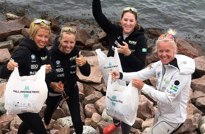 Fyra glada skräpplockare vid kusten